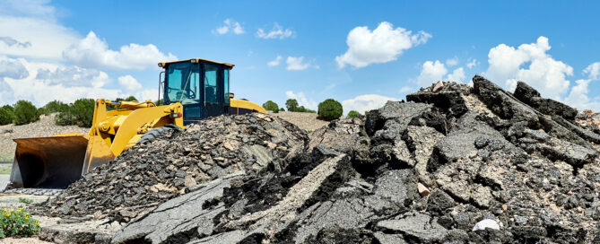 recycled asphalt piles with a loader in the background