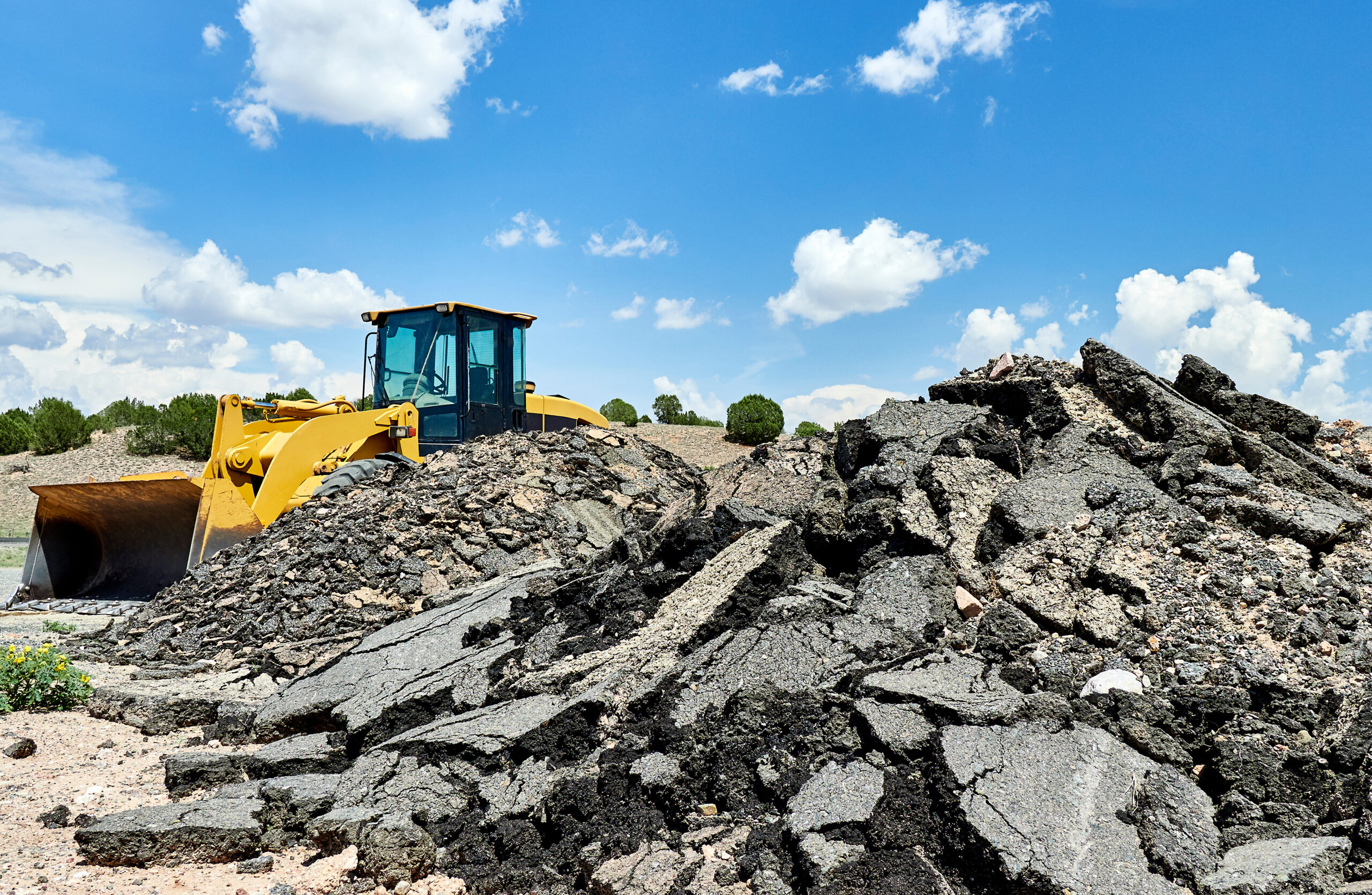 recycled asphalt piles with a loader in the background